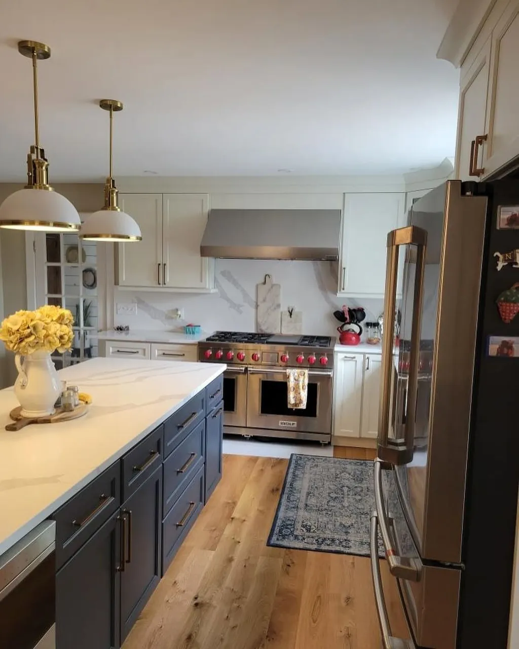 Kitchen remodeled by Delpa Builders in New Castle, Delaware, with slate blue island, veined countertops and brass pendants