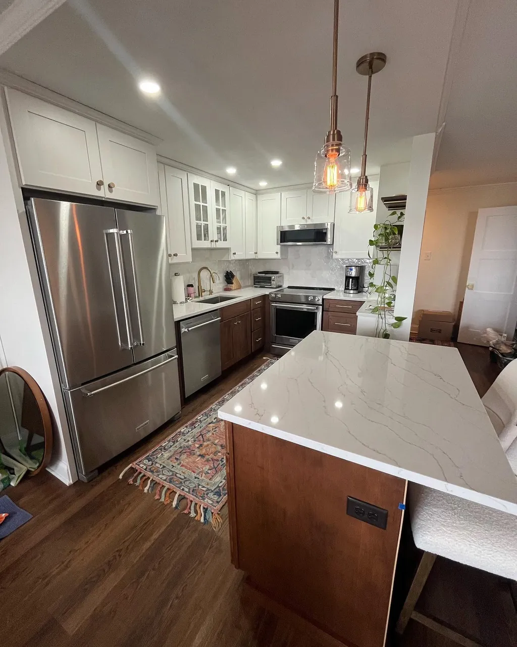 Kitchen remodel by Delpa Builders with wood cabinetry, white island and stainless appliances