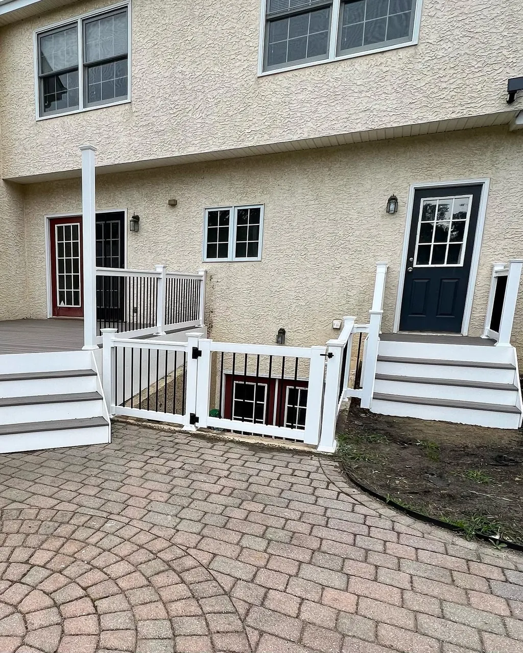 White railing and gate beside a paver courtyard by Delpa Builders